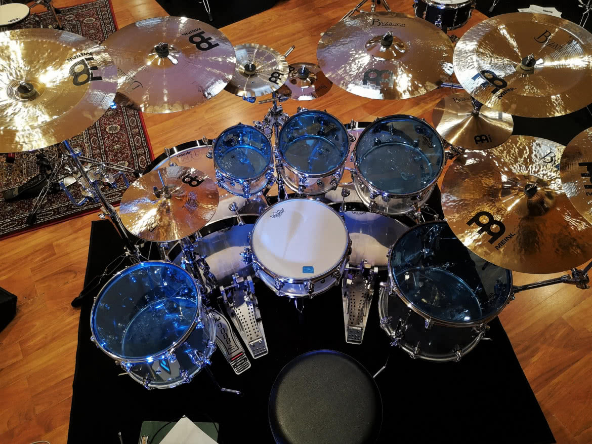 Akrylowe bębny DW Drums z talerzami Meinl, naciągami Remo i pałkami Vater. Widzimy też stopki DW.